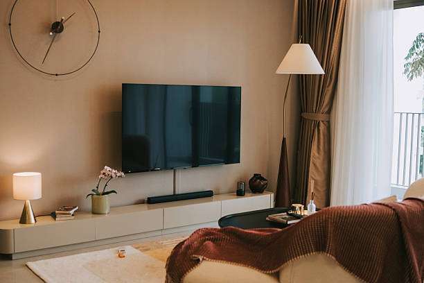 The space is complemented by a round black coffee table, floor-to-ceiling glass doors lamp shades