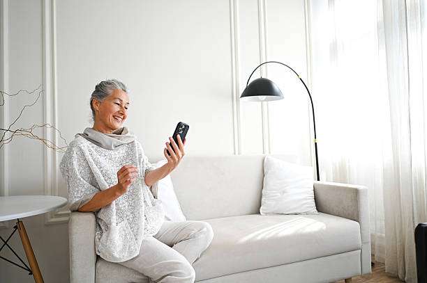 Smiling woman on couch with phone, arch lamp shades.