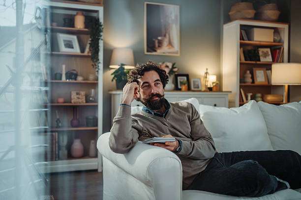 Man resting on couch near lamp shades.