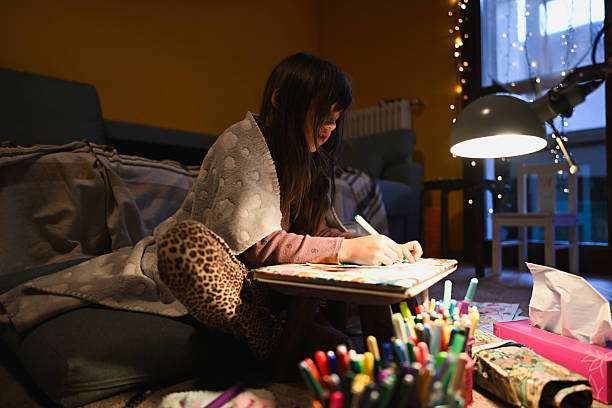 Girl drawing under a desk lamp with decorative lamp shades.
