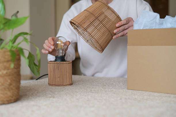 Assembling a natural bamboo lamp shade onto a table lamp.
