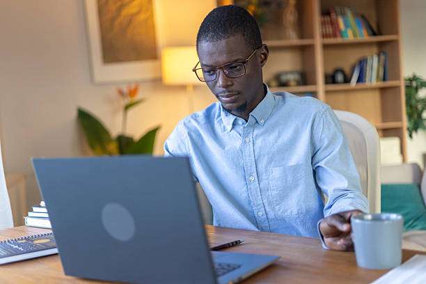 Man working on laptop near lamp shades.