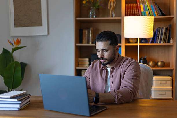 Man using laptop with modern lamp shades behind.