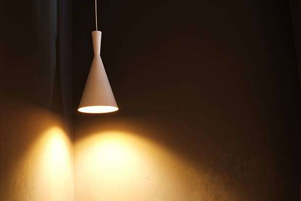 Minimalist white cone pendant lamp shades casting warm light on wall.